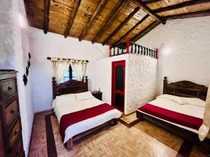 a bedroom with two beds and a wooden ceiling at Posada de Aquilino MC in Cucunubá +29 photos