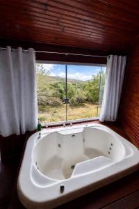 a bath tub in a room with a window at Pousada Árvore Centenária in São Thomé das Letras +26 photos