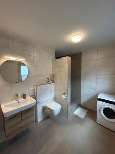 a bathroom with a toilet and a sink and a washing machine at Seebrise in Geeste