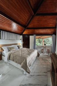 a bedroom with a large bed and wooden ceilings at Pousada Árvore Centenária in São Thomé das Letras