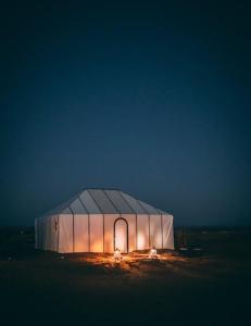 a large white tent with lights inside at night at Nomads Life Style in Mhamid