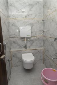 a bathroom with a white toilet and a pink sink at Hotel Midnight Lodging & Boarding in Panvel