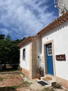 a white building with a blue door on the side at Casa Terra in Rio Maior