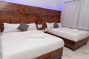 two beds in a hotel room with white sheets at Hotel Midnight Lodging & Boarding in Panvel