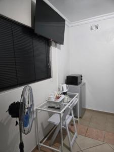 a small kitchen with a table and a fan at Cjabaledi Guesthouse in Centurion