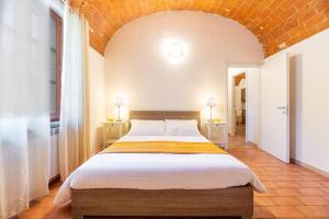 a bedroom with a large bed with a brick wall at Windrose Cottage di Gio in Pisa