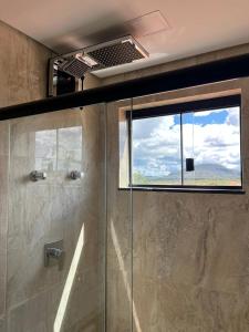 a shower with a glass door and a window at Residencial Canto dos Passarinhos - Loft e Apartamentos in Alto Paraíso de Goiás +32 photos