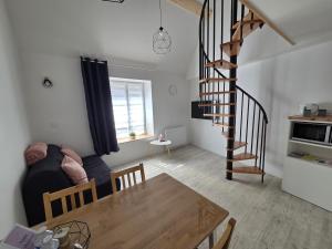a living room with a table and a spiral staircase at Nuit douce au LYS in Phalsbourg +5 photos