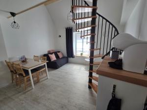 a living room with a table and a spiral staircase at Nuit douce au LYS in Phalsbourg