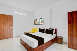 a bedroom with a bed and a yellow chair at Super Hotel O Destiny Inn in Pune