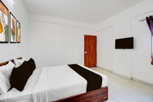 a white bedroom with a bed and a television at Super Hotel O Destiny Inn in Pune +20 photos
