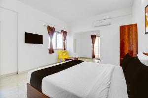 a bedroom with a white bed and a yellow chair at Super Hotel O Destiny Inn in Pune