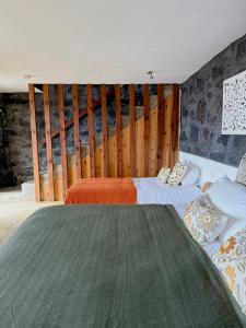 a bedroom with two beds and a wooden wall at Bruma do Pico House in Lajes do Pico