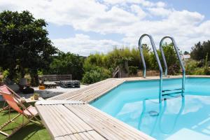 a swimming pool with a wooden deck and a chair next to it at Chitaka's Organic Farmhouse in Ribatejo in Santo Estêvão