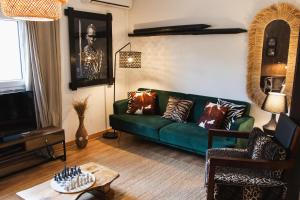 a living room with a green couch and a table at Chitaka's Organic Farmhouse in Ribatejo in Santo Estêvão