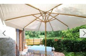 a table with a white umbrella on a patio at Il Boschetto in Le Grazie
