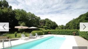 a swimming pool with chairs and umbrellas in a yard at Il Boschetto in Le Grazie