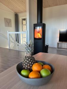 a bowl of fruit with a pineapple and oranges in front of a stove at Affordable Luxury Sauna Chalet - River Views in Vossevangen