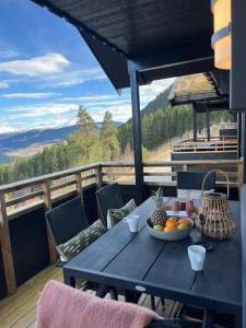 a table with a bowl of fruit on a balcony at Affordable Luxury Sauna Chalet - River Views in Vossevangen