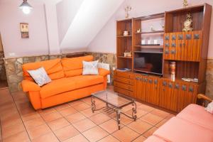 a living room with an orange couch and a tv at Casas Rurales La Dehesa in Casas del Monte