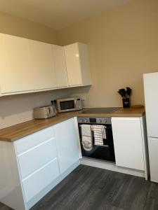 a kitchen with white cabinets and a black oven at West Highland Hideaway in Kinlochleven