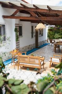 a patio with wooden benches and a table and chairs at Chitaka's Organic Farmhouse in Ribatejo in Santo Estêvão