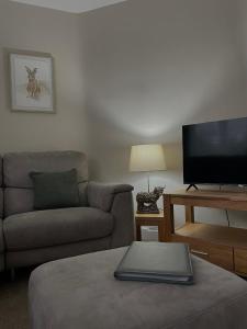 a living room with a couch and a flat screen tv at West Highland Hideaway in Kinlochleven +8 photos