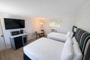 a hotel room with two beds and a flat screen tv at The Foxberry - A Digital Concierge Guesthouse in Provincetown