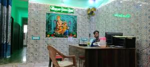 a man sitting at a desk in front of a computer at Mayapur Yatri Nivas in mayapur