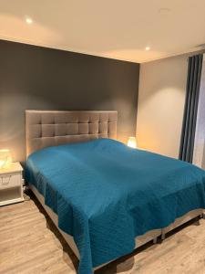 a bedroom with a bed with a blue bedspread at Sokkelleilighet in Grindheim