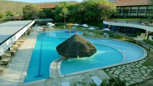 a swimming pool with a straw umbrella in a resort at Flat superior no Monte Castelo Condomínio in Gravatá