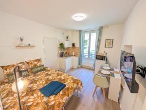 a small room with a bed and a table and a desk at Le Studio Évasion Tropicale in Quimper