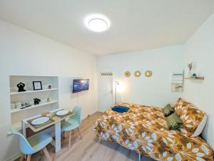 a bedroom with a bed and a desk and a table at Le Studio Évasion Tropicale in Quimper