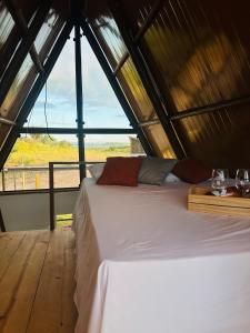 a bed in a room with a large window at Chalé Pontal da Juacema in Ilha Cachoeira
