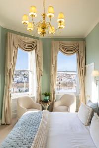a bedroom with a bed and two chairs and windows at The Royal Hotel in Bideford