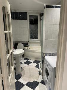 a bathroom with a tub sink and a washing machine at Jak w domu in Słupsk