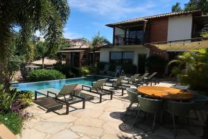 a patio with chairs and a table next to a pool at Pousada Villa Canaã in Búzios