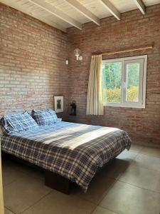 a bedroom with a large bed with a brick wall at Duplex Las Margaritas Bosque Peralta Ramos in Mar del Plata