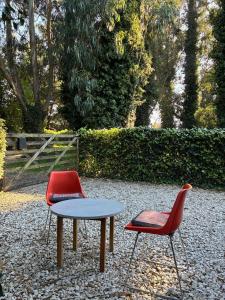 two red chairs and a table in a park at Duplex Las Margaritas Bosque Peralta Ramos in Mar del Plata +24 photos