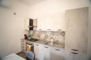 eine kleine Küche mit weißen Schränken und einer Spüle in der Unterkunft Penta House in Fisciano + 7 Fotos