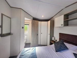 a bedroom with a large bed and a bathroom at Swanage Luxury Caravan - Stunning sea views, Large decking area, Free EE WIFI, Sleeps 6, Pet Friendly on Swanage Bay View Holiday Park in Swanage +197 photos