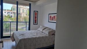 a bedroom with a bed and a large window at Seaside Piriápolis apartamento 105 in Piriápolis +12 photos