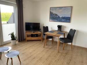 a living room with a table and chairs and a television at Ferienwohnung Watt n Deichblick in Friedrichskoog