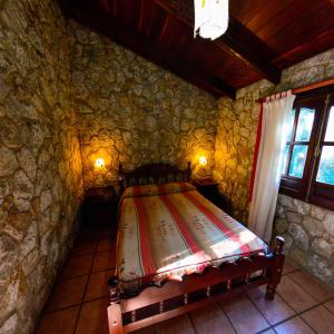 a bedroom with a bed in a stone wall at Pinar del Arroyito in Villa General Belgrano