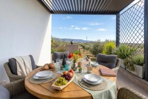 a wooden table with a bowl of fruit on a patio at Luxury Sunshine Villa in Alghero with pool and sea view in Alghero