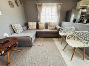 a living room with a couch and two chairs at The Valley View Nest in Ezulwini