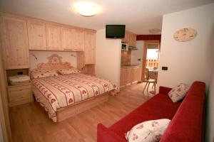 una camera con un letto e un divano rosso di Appartamenti Albert a Canazei