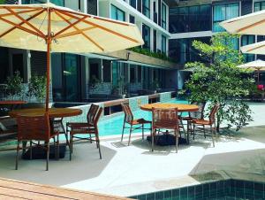 a patio with tables and chairs next to a pool at Sunny Hall Porto de Galinhas PE - Flat Piscina Privativa in Porto De Galinhas