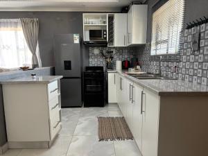a kitchen with white cabinets and a black refrigerator at The Valley View Nest in Ezulwini