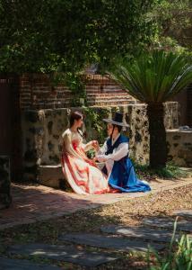 a man and woman in dresses sitting on a sidewalk at Stay Aeok Jeju in Seogwipo